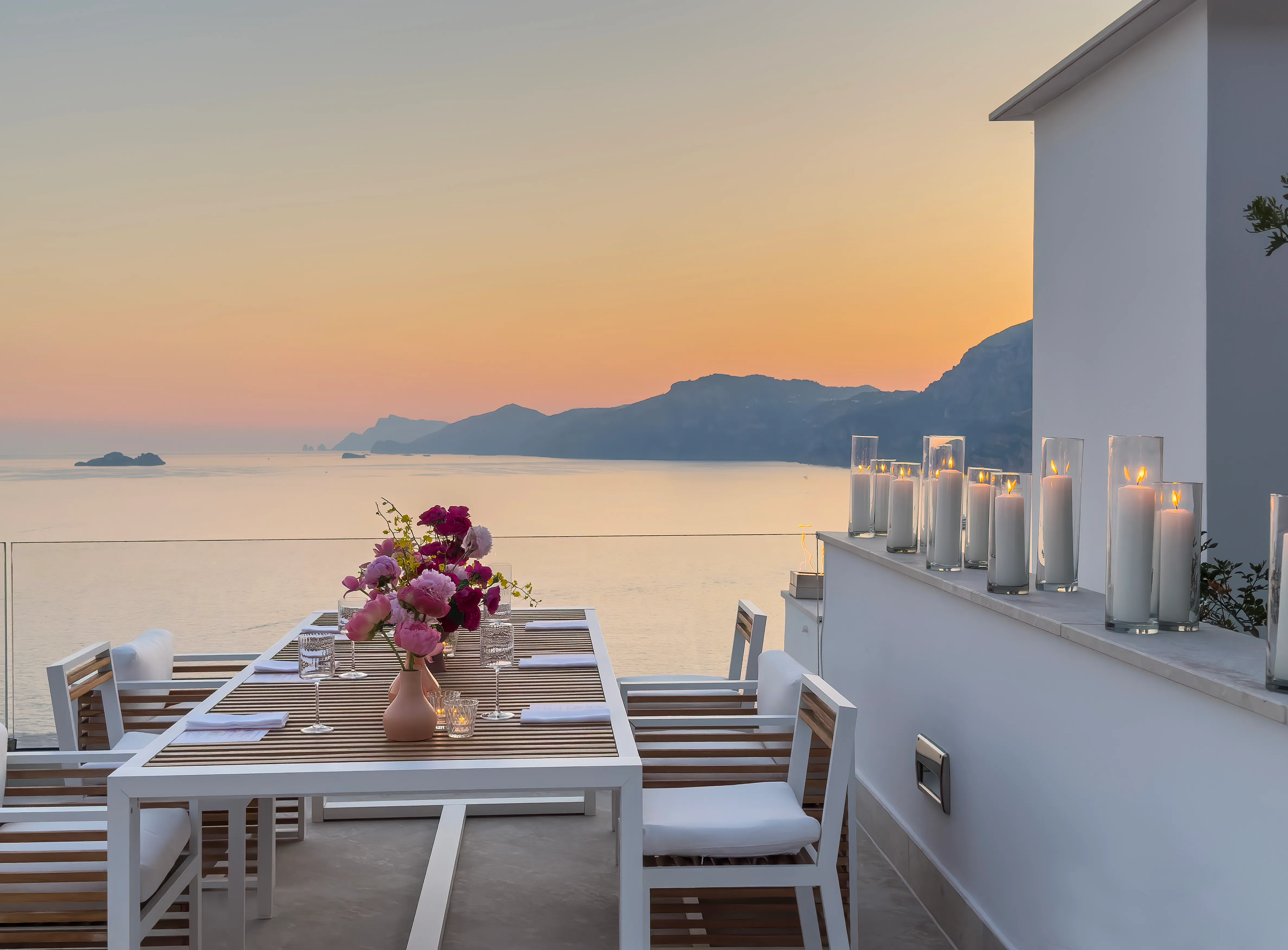 White terrace stepping down a cliff above the sea with a glass sculpture
